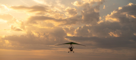 Propeller plane flies in the sunset sky. Banner, A small private hang-glider in a cloudy sky.の写真素材