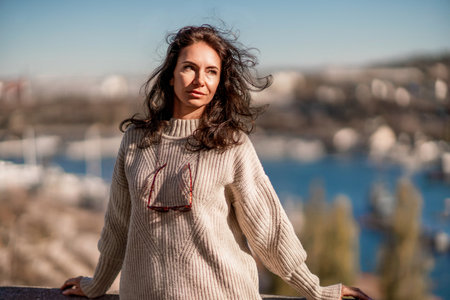 Woman walks in the city, lifestyle. Young beautiful woman in a loose light sweater, brown skirt and sneakers with a hat.の写真素材