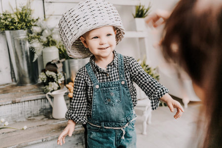 Little girl 1 years old with a basket on her head. Funny child plays puts a basket on her head like...