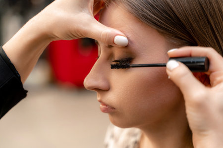 Makeup artist paints eyelashes to a woman in a beauty salon.の写真素材