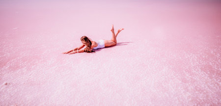Woman in a pink salt lake. She lies in a white bathing suit. Wanderlust photo for memoryの写真素材