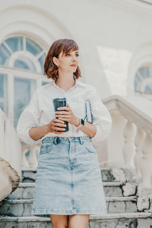 Woman staircase city. A business woman in a white shirt and denim skirt walks down the steps of an ancient building in the cityの写真素材