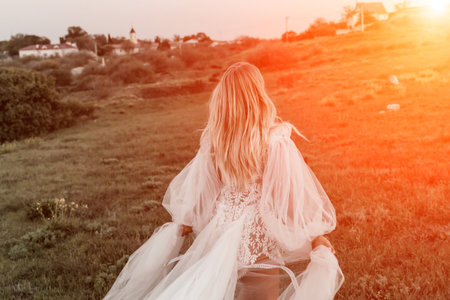 beautiful young bride in a field at sunsetの写真素材