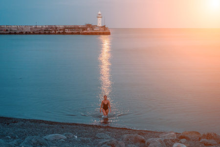 Woman The full moon rises to the lighthouse, the lunar path along the sea leads to the woman.の写真素材