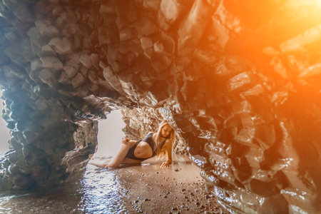 Woman travel sea. Attractive blonde woman in a black swimsuit enjoying the sea air on the seashore around the rocks. Travel and vacation concept.の写真素材