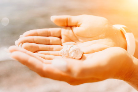 Beach vacation snapshot: A woman in a swimsuit holding a pebble in her hands, enjoying the serenity of the beach and the beauty of nature, creating a peaceful and relaxing atmosphere.の写真素材