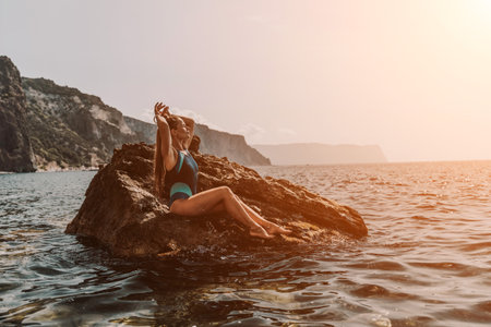 Woman travel summer sea. A happy tourist in a blue bikini enjoying the scenic view of the sea and volcanic mountains while taking pictures to capture the memories of her travel adventure.の写真素材