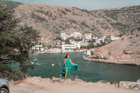 Woman sea trevel green dress. Side view a happy woman with long hair in a long mint dress posing on a beach with calm sea bokeh lights on sunny day. Girl on the nature on blue sky background.の写真素材