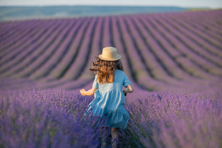 Lavender sunset girl. A girl in a blue dress with flowing hair in a hat runs through a lilac field of lavender. Aromatherapy travel.の写真素材