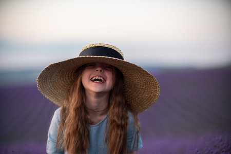 Girl lavender field. Laughing girl in a blue dress with flowing hair in a hat stands in a lilac lavender fieldの写真素材