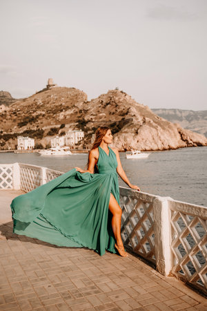 Woman sea trevel green dress. Side view a happy woman with long hair in a long mint dress posing on a beach with calm sea bokeh lights on sunny day. Girl on the nature on blue sky background.の写真素材