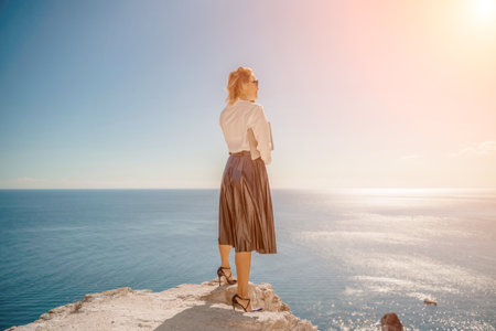 Freelance women sea working on a computer. Pretty middle aged woman with computer and phone outdoors with beautiful sea view. The concept of remote work.の写真素材