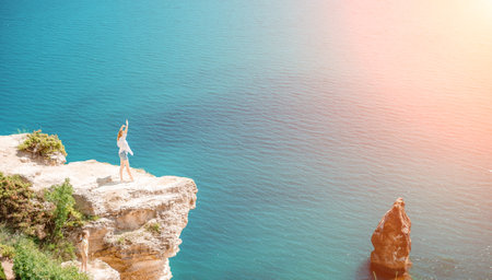 Woman travel summer sea. Portrait of a happy woman on a background of rocks and the sea. View of a woman in a white shirt and swimsuit. Freedom and happinessの写真素材