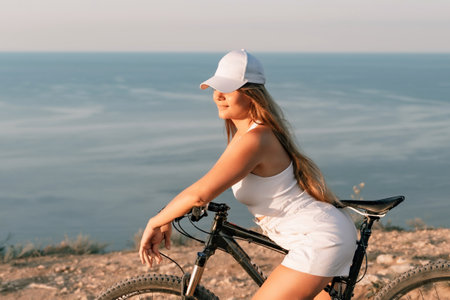 Foto de A woman cyclist on a mountain bike looking at the landscape sea. Adventure travel on bike. - Imagen libre de derechos