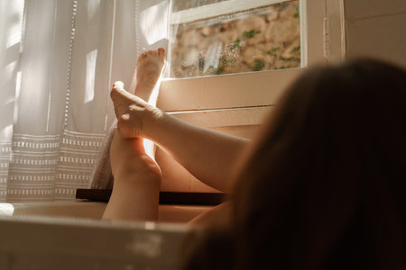 a beautiful mature woman massages her legs in a bath with candles in a cozy and comfortable atmosphereの写真素材