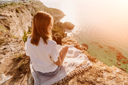 Freelance woman working on a laptop by the sea, typing away on the keyboard while enjoying the beautiful view, highlighting the idea of remote work.の写真素材