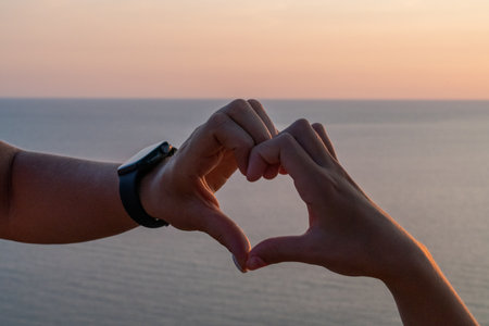 Hands heart sea sanset. Hands forming a heart shape made against the sun sky of a sunrise or sunset on a beachの写真素材