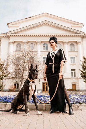 A photo of a woman and her Great Dane walking through a town, taking in the sights and sounds of the urban environment.の写真素材