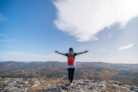 woman backpack on mountain peak looking in beautiful mountain valley in autumn. Landscape with sporty young woman, blu sky in fall. Hiking. Natureの写真素材