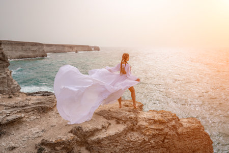Woman sea white dress. Happy freedom woman on the beach enjoying and posing in white dress. Rear view of a girl in a fluttering white dress in the wind. Holidays, holidays at sea.の写真素材