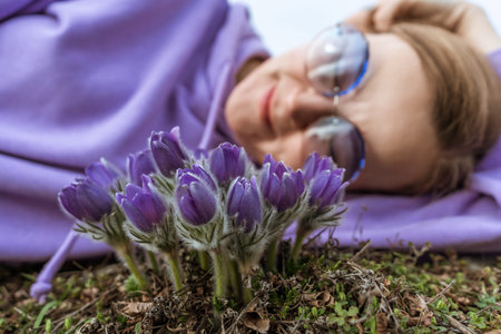 Dream grass woman spring flower. Woman lies on the ground and hugs flowers pasqueflower or...