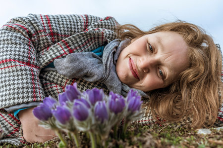 Dream grass woman spring flower. Woman lies on the ground and hugs flowers pasqueflower or Pulsatilla Grandis flowersの写真素材