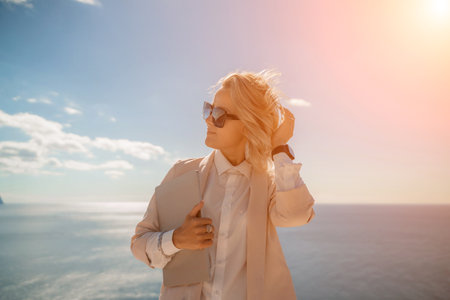 Freelance women sea working on a computer. Pretty middle aged woman with computer and phone outdoors with beautiful sea view. The concept of remote work.の写真素材