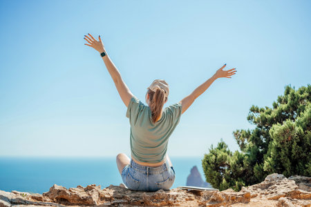 Woman tourist sky sea. Happy traveller woman in hat enjoys vacation raised her hands upの写真素材