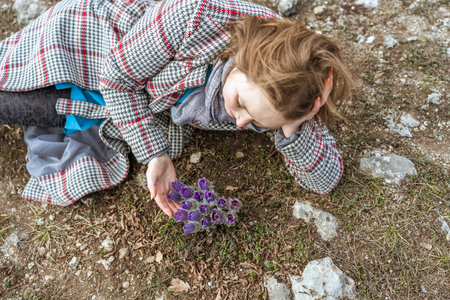 Dream grass woman spring flower. Woman lies on the ground and hugs flowers pasqueflower or Pulsatilla Grandis flowersの写真素材