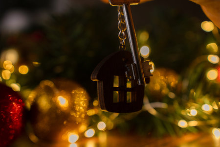 Gift key house with a keychain backdrop of Christmas tree. Building, design, project, moving to new...