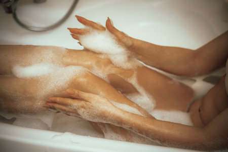 Womens feet in bath foam. View from above. Enjoy and relax in a spa hotelの写真素材