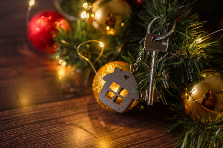Gift key house with a keychain backdrop of Christmas tree. Building, design, project, moving to new...