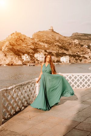 Woman sea trevel green dress. Side view a happy woman with long hair in a long mint dress posing on...