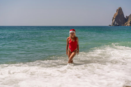 A woman in Santa hat on the seashore, dressed in a red swimsuit. New Years celebration in a hot countryの写真素材