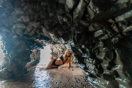 Woman swimsuit sea. Attractive blonde woman in a black swimsuit enjoying the sea air on the seashore around the rocks. Travel and vacation concept.の写真素材