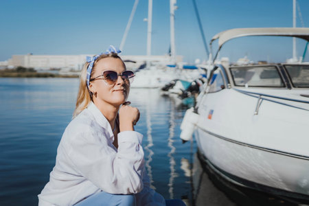 Woman in white shirt in marina , surrounded by several other boats. The marina is filled with boats of various sizes, creating a lively and picturesque atmosphere.の写真素材
