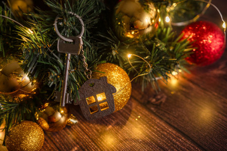 Gift key house with a keychain backdrop of Christmas tree. Building, design, project, moving to new house, mortgage, rent and purchase real estate. A gift for New Year, Christmasの写真素材