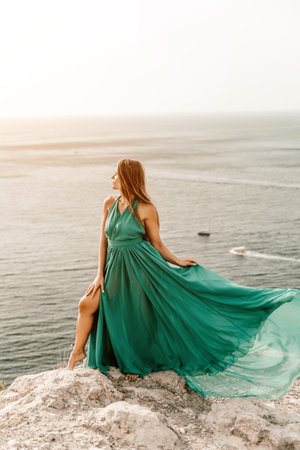 Woman sea trevel green dress. Side view a happy woman with long hair in a long mint dress posing on a beach with calm sea bokeh lights on sunny day. Girl on the nature on blue sky background.の写真素材