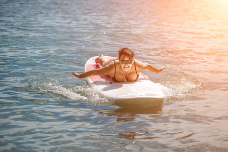 Woman sup sea travel. Sports girl on a surfboard in the sea on a sunny summer day. In a black...