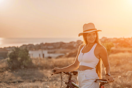 Woman travel bike. Happy woman cyclist sitting on her bike, enjoying the beautiful mountain and sea landscape, signifying the idea of an adventurous bike ride.の写真素材