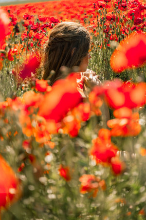 Woman poppies field. portrait happy woman with long hair in a poppy field and enjoying the beauty of nature in a warm summer day.の写真素材