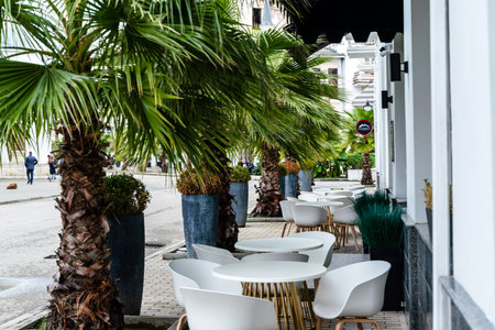 Street cafe with white chairs, green foliage around. Without people, tourism, travel.の写真素材