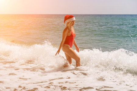 A woman in Santa hat on the seashore, dressed in a red swimsuit. New Years celebration in a hot countryの写真素材
