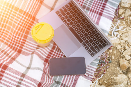 Laptop on blanket with ocean view. Illustrating serene outdoor laptop use. Freelancer enjoying their...