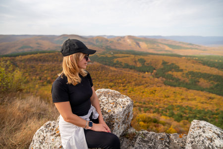 woman on mountain peak looking in beautiful mountain valley in autumn. Landscape with sporty young...