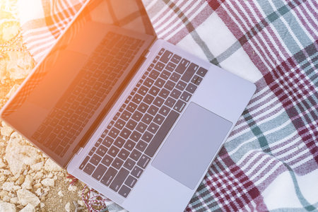 Laptop on blanket with ocean view. Illustrating serene outdoor laptop use. Freelancer enjoying their...