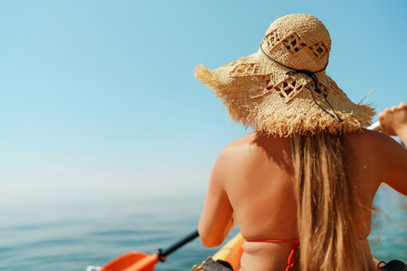Woman in kayak back view. Happy woman with long hair in a swimsuit and hat floating in kayak on the sea. Summer holiday vacation. Summer holidays vacation at sea.の写真素材
