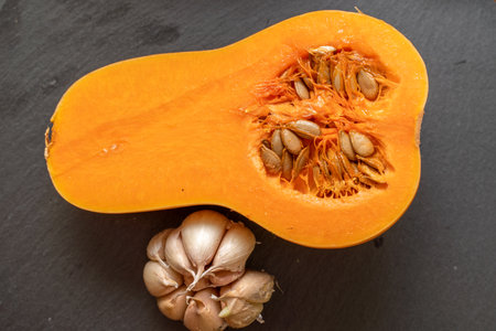 Orange pumpkin and garlic vegetable on a black background. Head of garlic. Halloween holiday. Agriculture food photo, background image.の写真素材