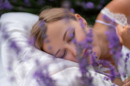 A middle-aged woman lies in a lavender field and enjoys aromatherapy. Aromatherapy concept, lavender oil, photo session in lavenderの写真素材