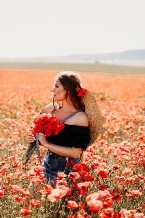 Woman poppies field. portrait happy woman with long hair in a poppy field and enjoying the beauty of nature in a warm summer day.の写真素材